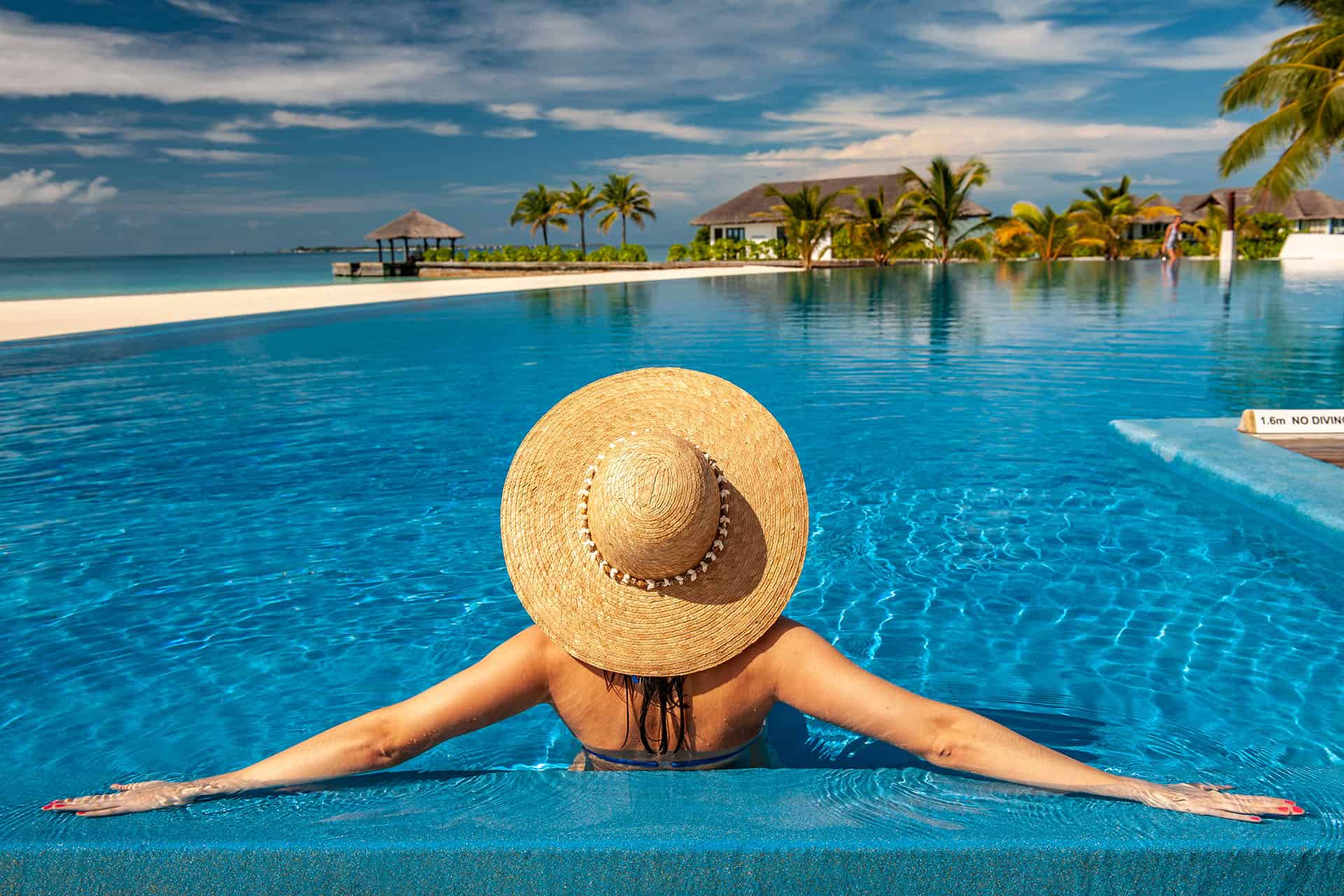 Woman with sun hat at beach pool in Maldives